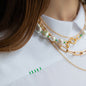 Nahaufnahme von weißer Bluse WEDNESDAY mit grünen Details und Necklace Layering in Gelbgold