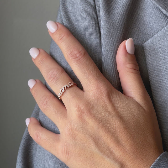 Hand mit Ring in Roségold mit weißen Diamanten und Aufschrift Mama